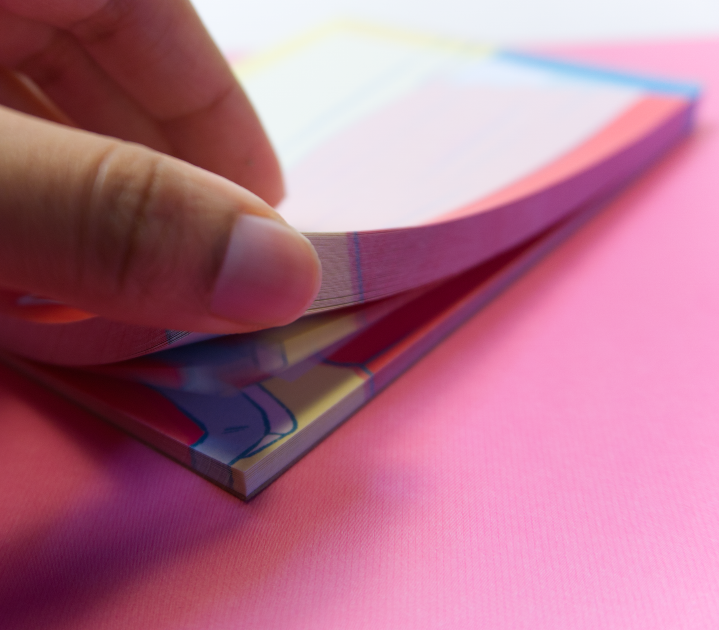 A hand flipping through the pages of a notepad.
