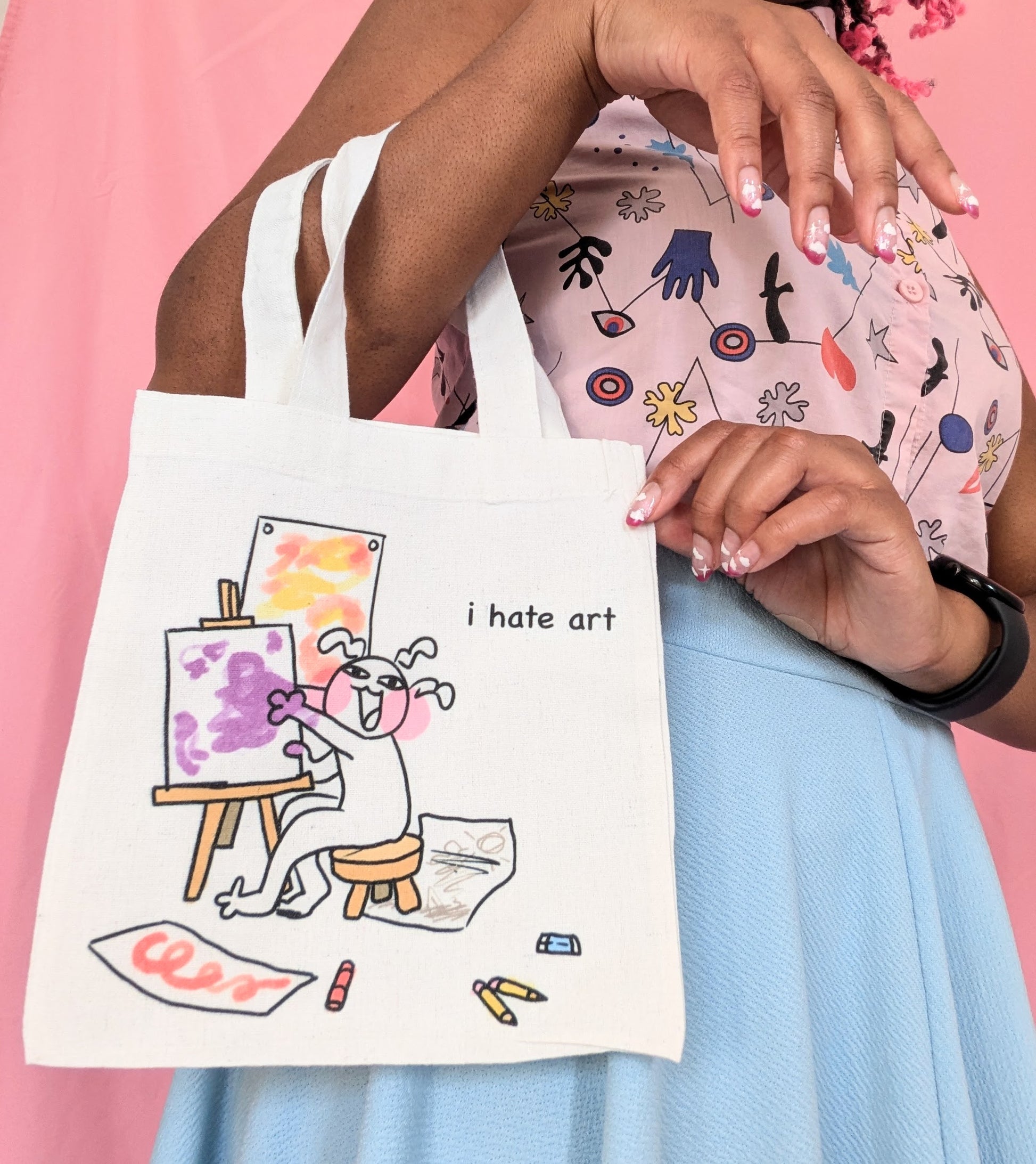 Model holding the I Hate Art small tote bag on their arm, their other hand holding the top right corner.