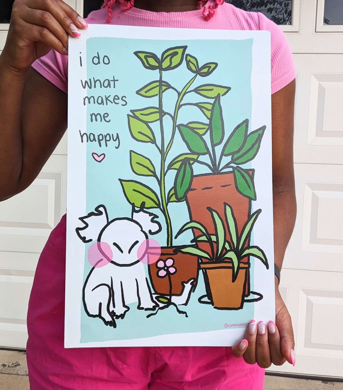 A poster depicting a cartoonish character with a content expression sitting on the floor. To the left of them sits 3 large potted plants. A single pink pansy flower is sprouting from the ground in front of the plants and the character. Black text above the character reads, ‘I do what makes me happy.’ with a small pink heart under it.